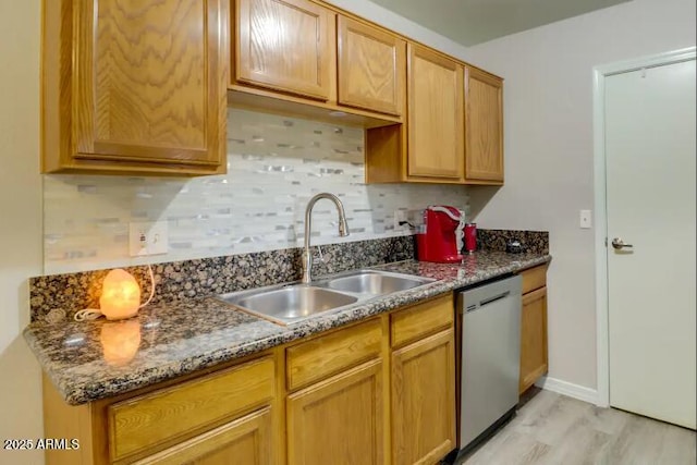 kitchen featuring a sink, baseboards, dishwasher, light wood-style floors, and tasteful backsplash