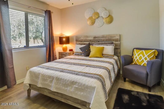 bedroom with wood finished floors and baseboards