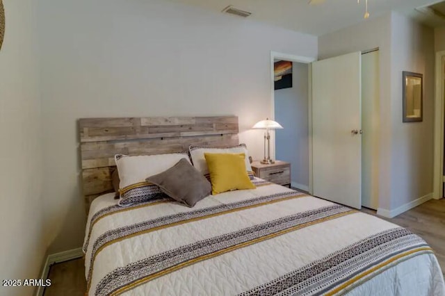 bedroom featuring baseboards, visible vents, and wood finished floors