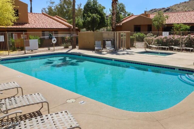 community pool featuring fence, a patio, and a community hot tub