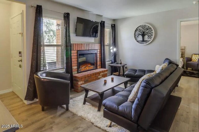 living area with baseboards, a brick fireplace, and light wood-type flooring