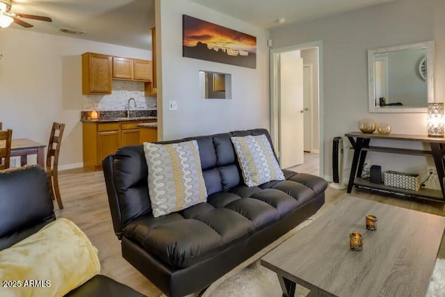 living room with light wood-style flooring, baseboards, and a ceiling fan