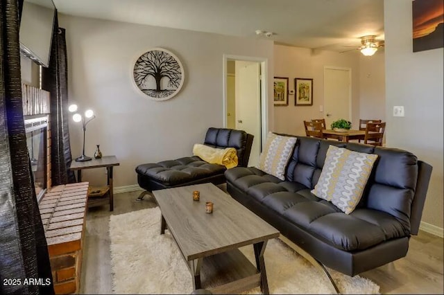 living room with baseboards, ceiling fan, and wood finished floors