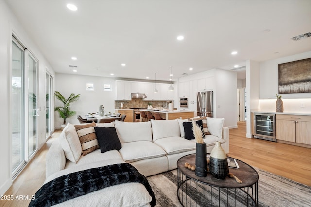 5537 E Earll Dr, Phoenix, AZ 85018 - living area featuring beverage cooler, light wood finished floors, recessed lighting, and bar