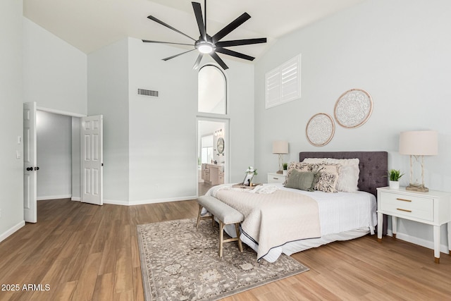 bedroom with ceiling fan, high vaulted ceiling, hardwood / wood-style floors, and ensuite bath