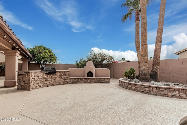 view of patio / terrace featuring a grill, an outdoor stone fireplace, and exterior kitchen