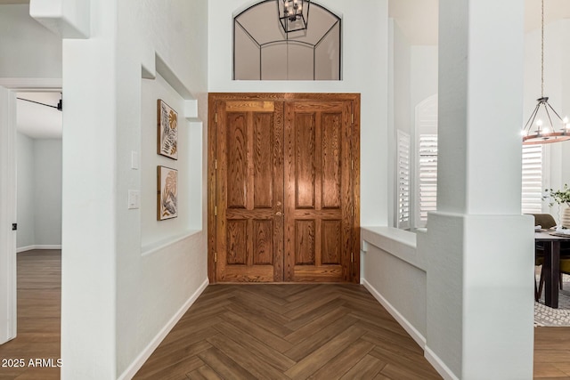 entryway featuring an inviting chandelier, parquet flooring, and a healthy amount of sunlight