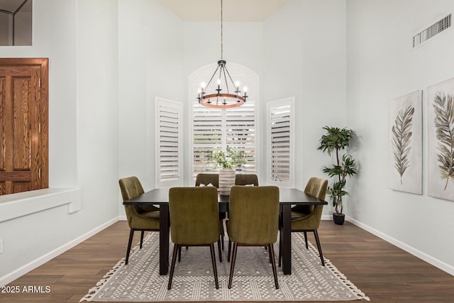 dining space featuring a high ceiling, dark wood-type flooring, and a notable chandelier