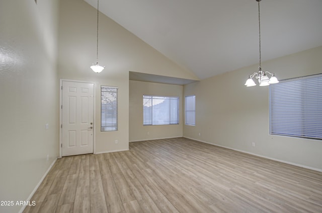 foyer entrance with high vaulted ceiling, light wood-type flooring, and a chandelier