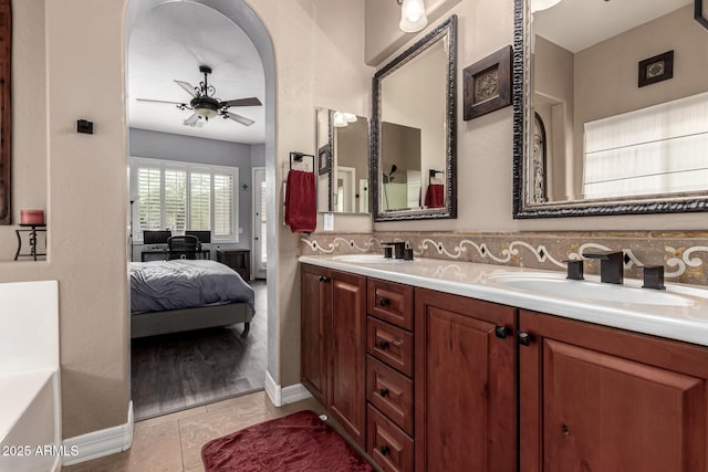 bathroom with ceiling fan, vanity, a bathtub, and decorative backsplash