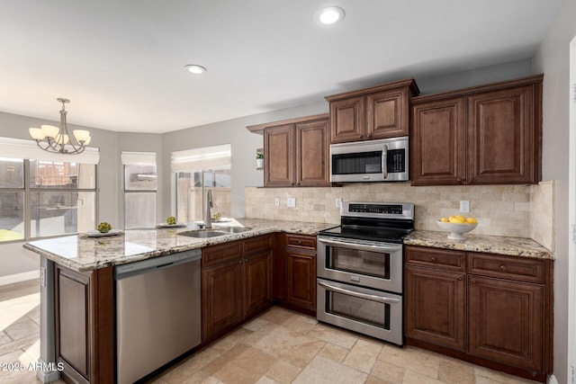 kitchen featuring decorative light fixtures, appliances with stainless steel finishes, sink, and kitchen peninsula