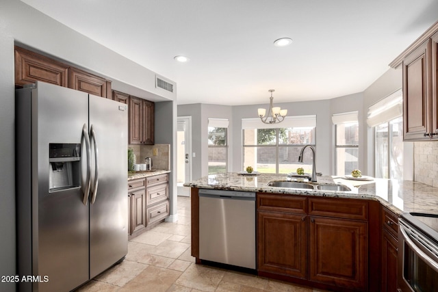 kitchen featuring light stone countertops, appliances with stainless steel finishes, sink, and backsplash