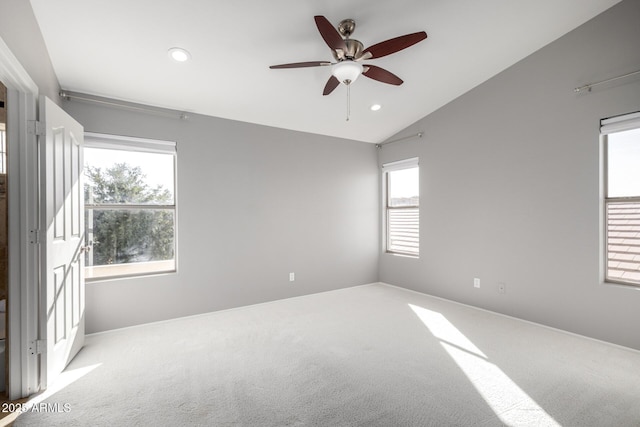 carpeted spare room featuring vaulted ceiling and ceiling fan