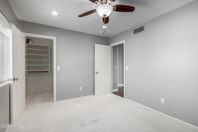 carpeted bedroom featuring a walk in closet, ceiling fan, and a closet