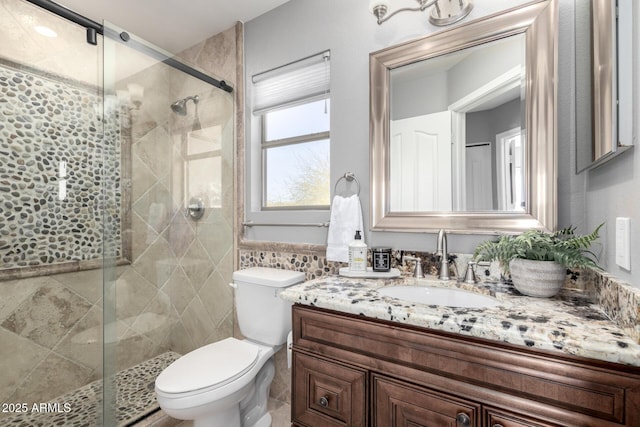 bathroom featuring vanity, toilet, a shower with shower door, and tile walls