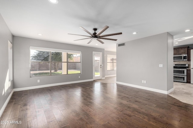 unfurnished living room featuring dark wood-type flooring and ceiling fan