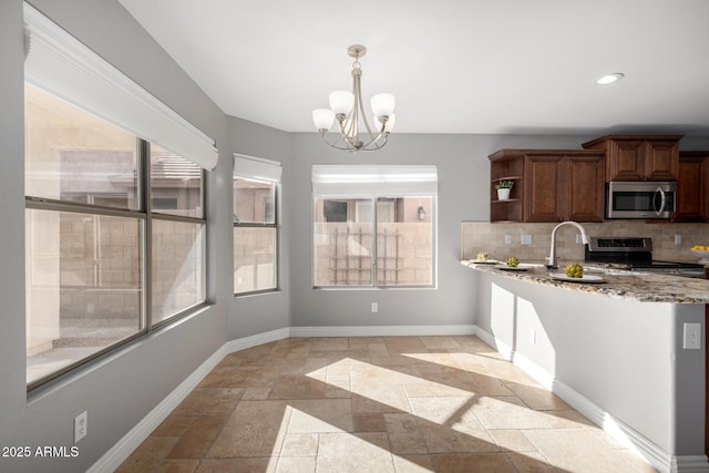 kitchen with light stone counters, appliances with stainless steel finishes, decorative backsplash, and a wealth of natural light