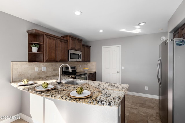 kitchen with light stone counters, dark brown cabinets, kitchen peninsula, stainless steel appliances, and decorative backsplash