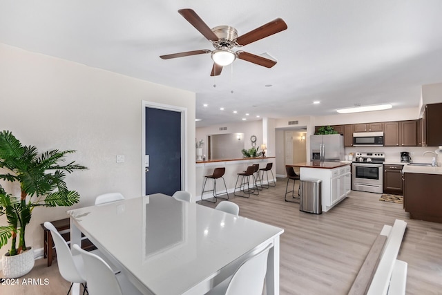 dining room with ceiling fan, sink, and light wood-type flooring