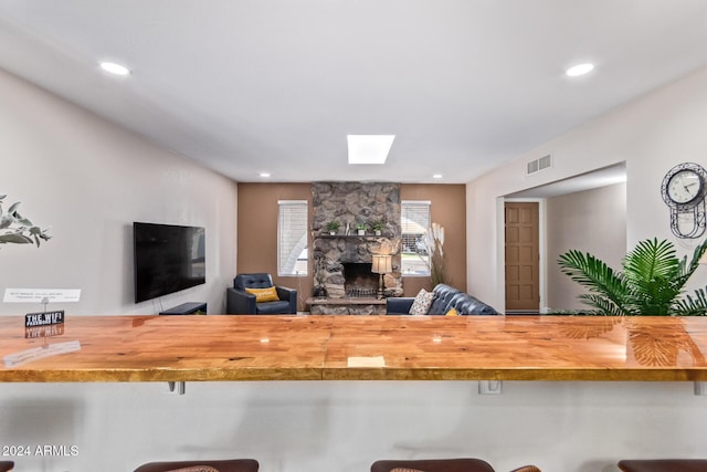 kitchen with a kitchen bar, butcher block counters, and a fireplace