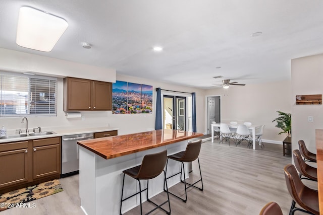 kitchen with sink, a breakfast bar area, wooden counters, a center island, and stainless steel dishwasher