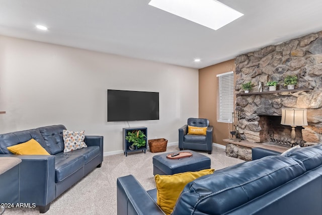 living room featuring a stone fireplace, light colored carpet, and a skylight