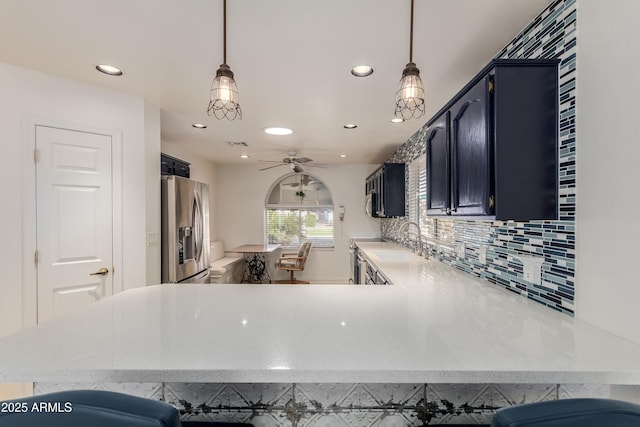 kitchen with tasteful backsplash, recessed lighting, a sink, a peninsula, and stainless steel fridge with ice dispenser