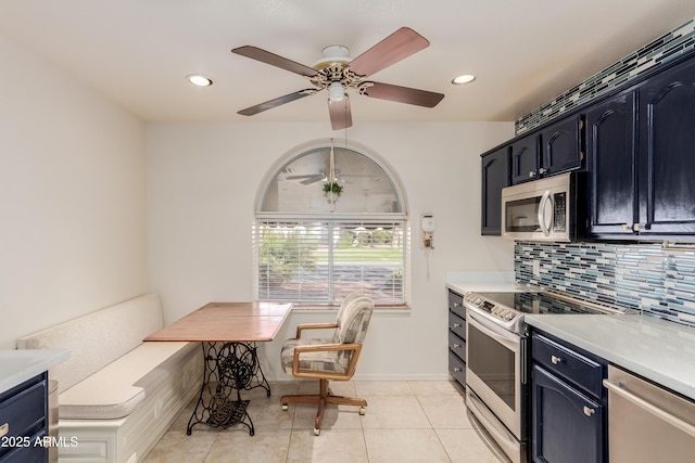 kitchen featuring stainless steel appliances, light tile patterned flooring, backsplash, and light countertops