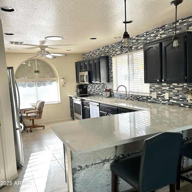 kitchen featuring plenty of natural light, visible vents, appliances with stainless steel finishes, dark cabinetry, and backsplash