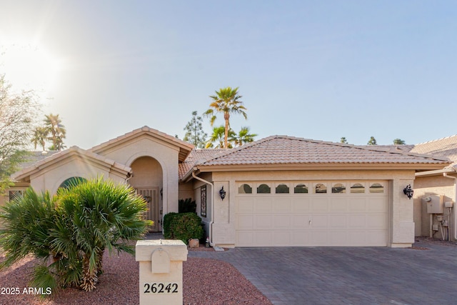 view of front of property with a garage, a tiled roof, decorative driveway, and stucco siding