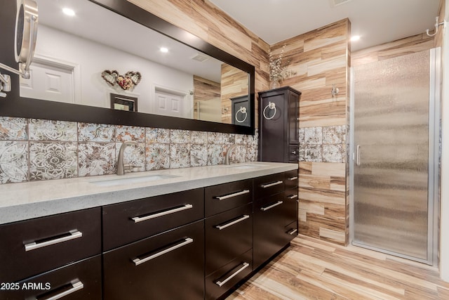 kitchen featuring light wood-style flooring, light stone counters, dark brown cabinets, and a sink