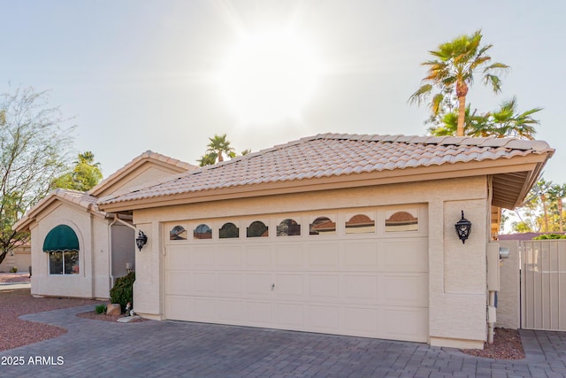 view of front of home with a garage, a tile roof, decorative driveway, and stucco siding