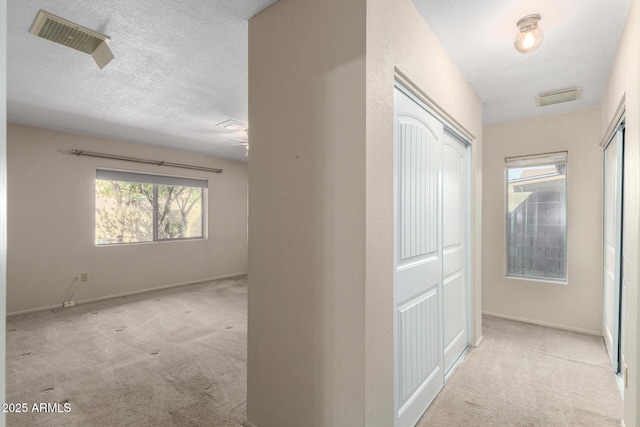 corridor featuring carpet, visible vents, and a textured ceiling