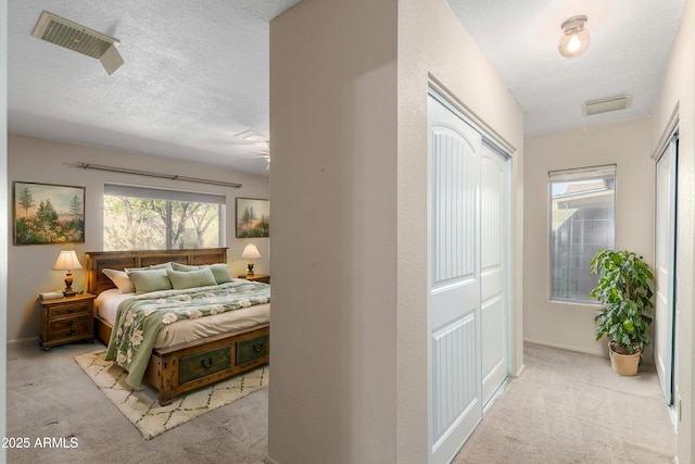 carpeted bedroom with visible vents, a textured ceiling, and baseboards