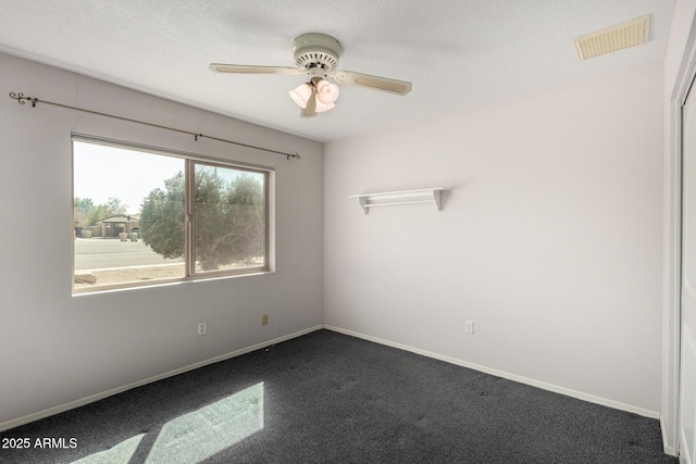 unfurnished room featuring dark colored carpet, visible vents, ceiling fan, and baseboards