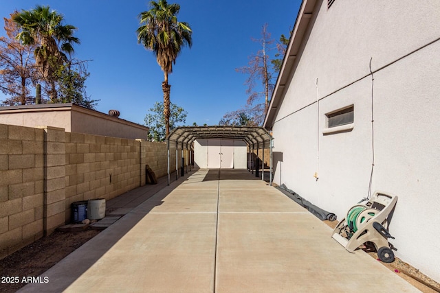 exterior space with a detached carport, driveway, fence, and stucco siding