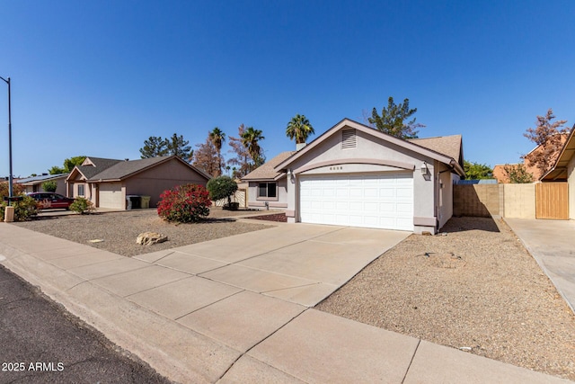 ranch-style house featuring a garage, concrete driveway, fence, and stucco siding