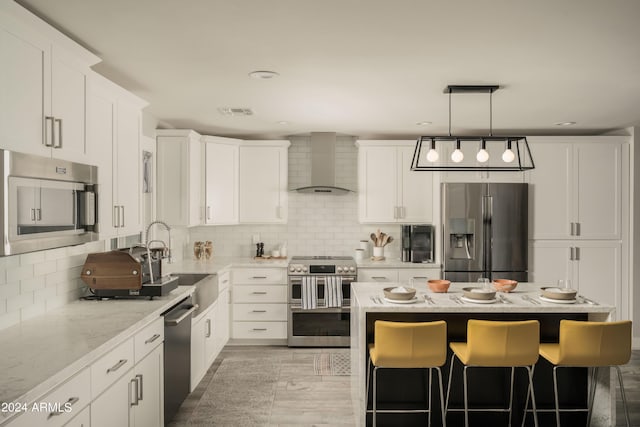 kitchen featuring white cabinetry, wall chimney exhaust hood, stainless steel appliances, light stone counters, and decorative light fixtures