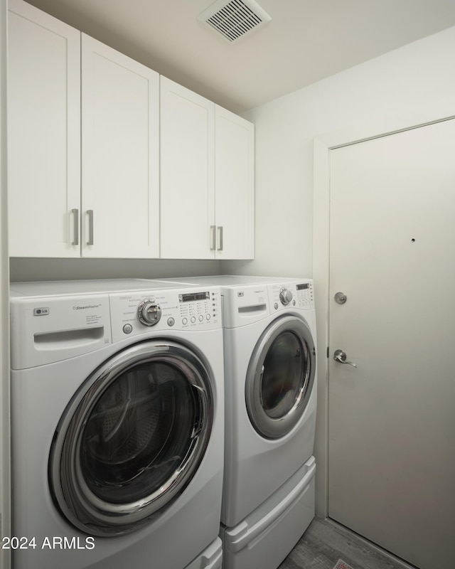 washroom with cabinets, washing machine and dryer, and dark hardwood / wood-style floors