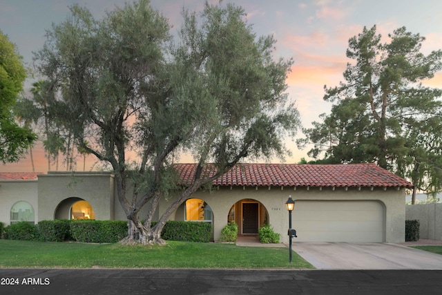 mediterranean / spanish-style home with a garage and a yard