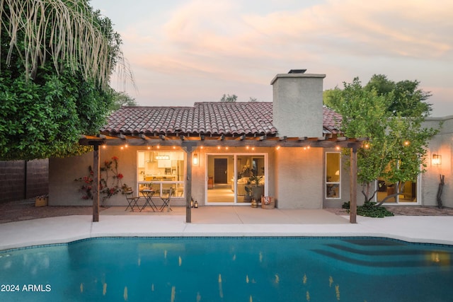 pool at dusk with a patio area