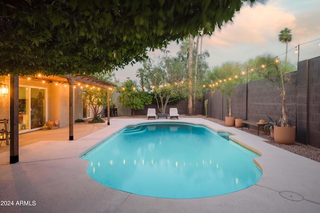 pool at dusk with a patio area