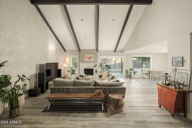 living room with beam ceiling, light wood-type flooring, and high vaulted ceiling