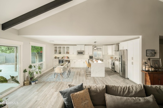 living room with vaulted ceiling with beams and light hardwood / wood-style flooring