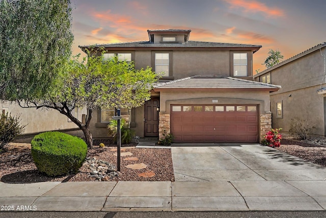 view of front of house featuring a garage, stone siding, concrete driveway, and stucco siding