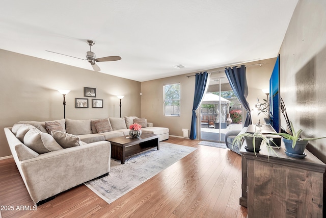 living room featuring a ceiling fan, wood finished floors, visible vents, and baseboards