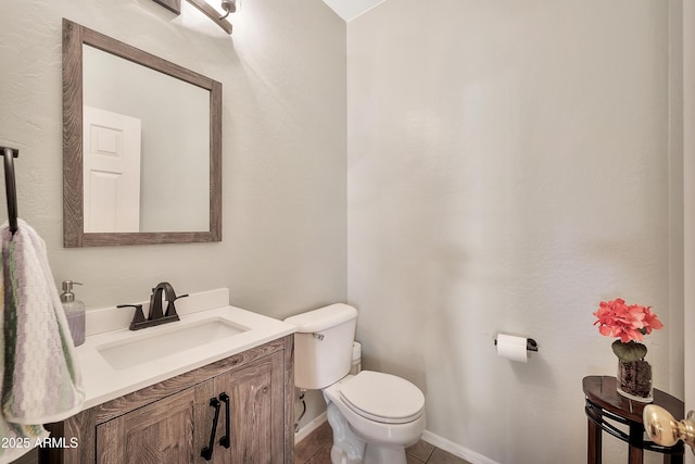 half bathroom with tile patterned floors, toilet, vanity, and baseboards