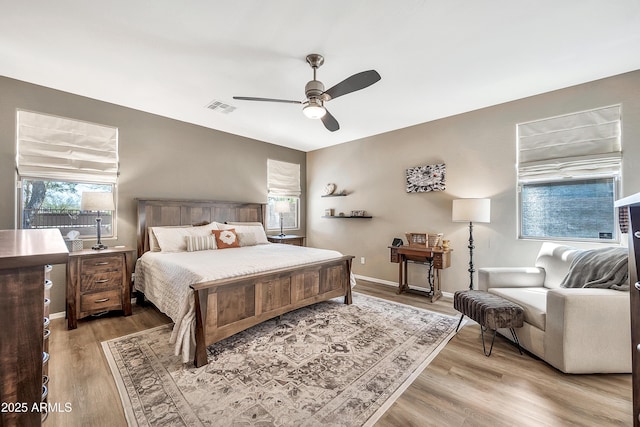 bedroom with a ceiling fan, light wood-style floors, visible vents, and baseboards