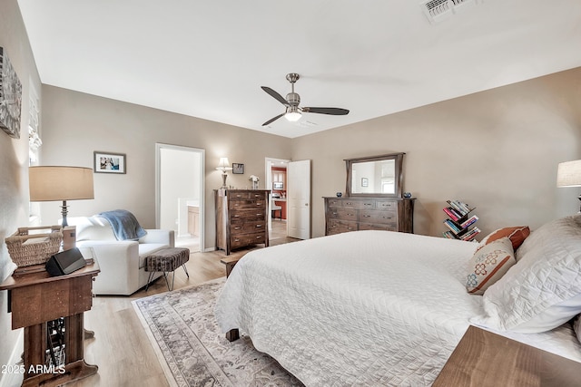 bedroom featuring ensuite bathroom, a ceiling fan, visible vents, and light wood finished floors