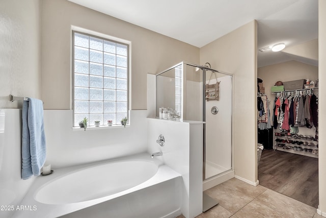 full bathroom with a garden tub, a stall shower, a spacious closet, and tile patterned flooring